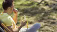 A man sitting on a park bench and eating a banana before a workout.