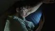 A man lying in bed and staring at his phone at night.