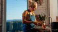 A middle-aged woman making mindful menopause nutrition choices by making a healthy salad. She's standing in her modern kitchen and chopping an onion.