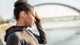 A woman standing outside and holding her hand to her face as she suffers from a headache after a workout.