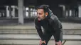 A man catching his breath after a run, with his hands on his knees. He is not hungry after his workout.