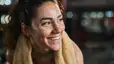 A happy, sweaty athlete smiling and looking to the side. There's a towel around her neck.