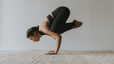 Woman practices Crow Pose, and advanced yoga pose