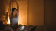 Woman stretches while sitting on bed