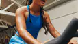 Young woman doing a HIIT workout on a Peloton Bike at the gym