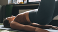 Woman doing glute bridges as the gym wondering what it means to be in a neutral spine during exercise.