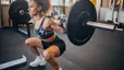 Woman does a barbell squat in gym