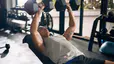 A young man does incline dumbbell chest presses at the gym to build chest muscles