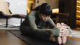 Woman doing a Seated Forward Fold in her living room at home during a practice of seated yoga poses