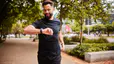 Man checking watch while running outside