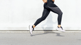 Close up shot of a woman's legs while she's running strides outside.