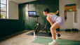 Woman engaging in hybrid training by doing a Peloton kettlebell strength class on her Bike+.