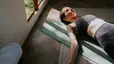 Woman laying on exercise mat in sunlight doing Pilates breathing exercises