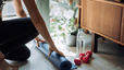 Woman rolling out exercise mat for a home workout deciding whether to do Pilates vs weight training