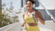 Woman running outside with headphones on holding a water bottle
