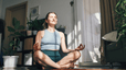 A woman meditating at home in the sunlight as part of her morning routine.
