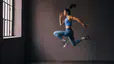 Woman does a jumping exercise indoors, an explosive exercise 