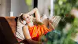 A woman resting in the sunlight at home while listening to music.