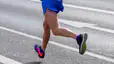 A close-up view of a runner's legs running on an outdoor paved road.