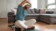 A man taking a rest day from exercise and doing some gentle stretches at home on a workout mat.