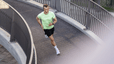 A man running outside on a footbridge. 