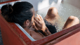 A man taking an ice bath and holding his hands to his face. Learn about cold showers vs. ice baths in this article.
