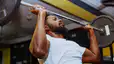 A man lifting a barbell at the gym.