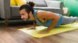 A man in Plank Pose on a yellow yoga mat at home. He is doing yoga to build muscle.