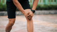 Is running bad for your knees? Man holds his knee while pausing during a run