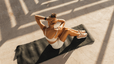 A woman doing a core workout while sitting on a yoga mat outside.