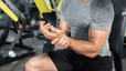 Close-up photo of a man holding his left wrist in the gym. He is dealing with wrist pain from weight lifting.