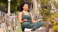 Woman meditating outside on a park bench in workout clothes