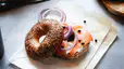 An everything bagel with cream cheese, salmon, red onions, and capers resting on a brown parchment bag.