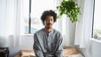 A man meditating at home in a sunny room as part of his habit loop.