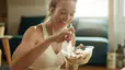 A smiling woman eating a salad after a workout.