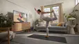 Woman practices a dancer pose at home. 