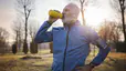 Man drinks from his water bottle while running