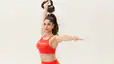 Peloton instructor Assal Arian holding a kettlebell above her head