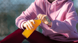 A woman drinking an orange electrolyte drink before or after a workout.