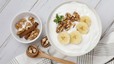 A bowl of Greek yogurt with banana and walnuts.