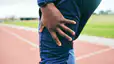 A close-up photo of a man holding his thigh as he experiences a muscle twitch after a workout.