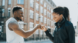 Man and woman fistbumping outside