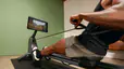 man learning how to use a rowing machine on a Peloton Row scenic class