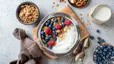 A bowl of yogurt, berries, and granola with an aesthetically pleasing table setting. Yogurt and berries are great foods for gut health. Learn more about what gut health is in this article.