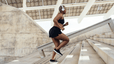 A woman running up a set of outdoor stairs in warm weather.