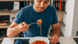 A man eating spaghetti as he carb loads.