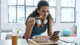 A woman eating after a workout and looking at her phone.