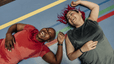 Two women lying down on a colorful exercise mat after exercising, laughing. Exercising is a great way to activate your "happy hormones."