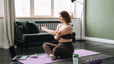 A woman sitting down on a yoga mat, stretching her arms on a rest day.