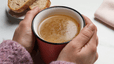 Close-up photo of a pair of hands holding a cup of bone broth.